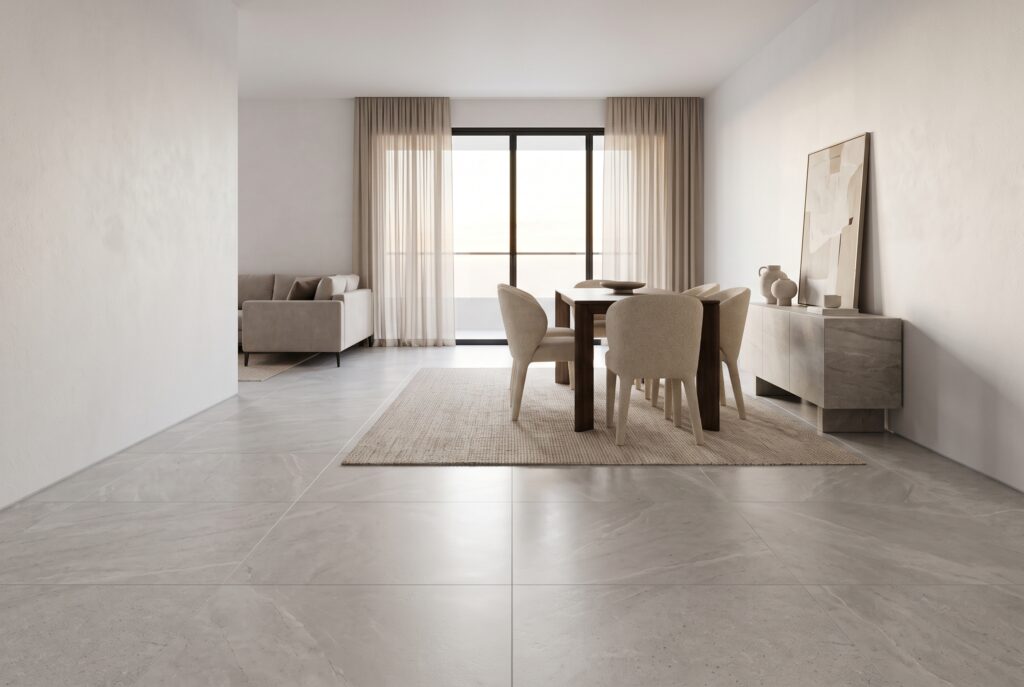 Sala comedor con piso de porcelanato de gran formato efecto piedra caliza gris clara, mesa de madera oscura y luz natural de tarde