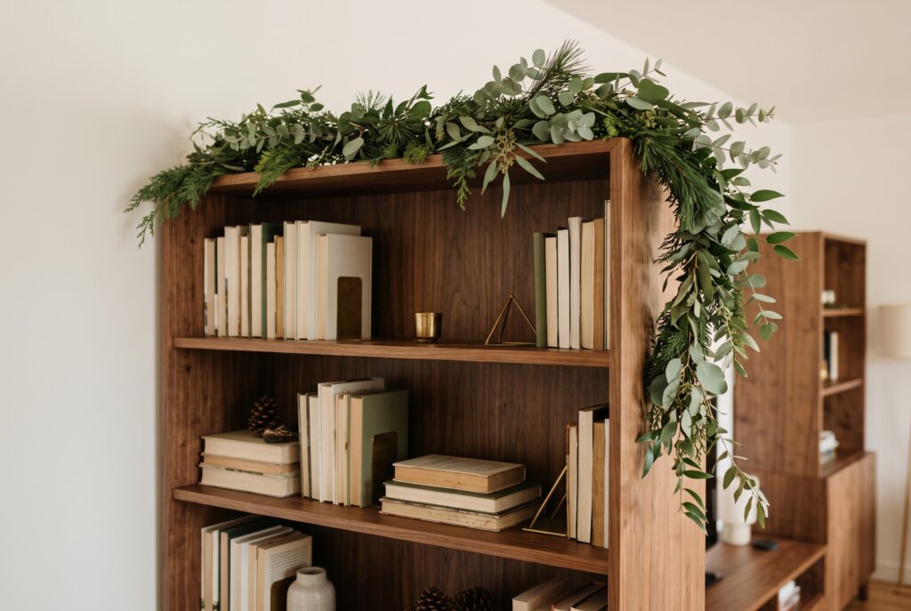Guirnalda de ramas verdes sobre una estantería de madera con libros y adornos dorados